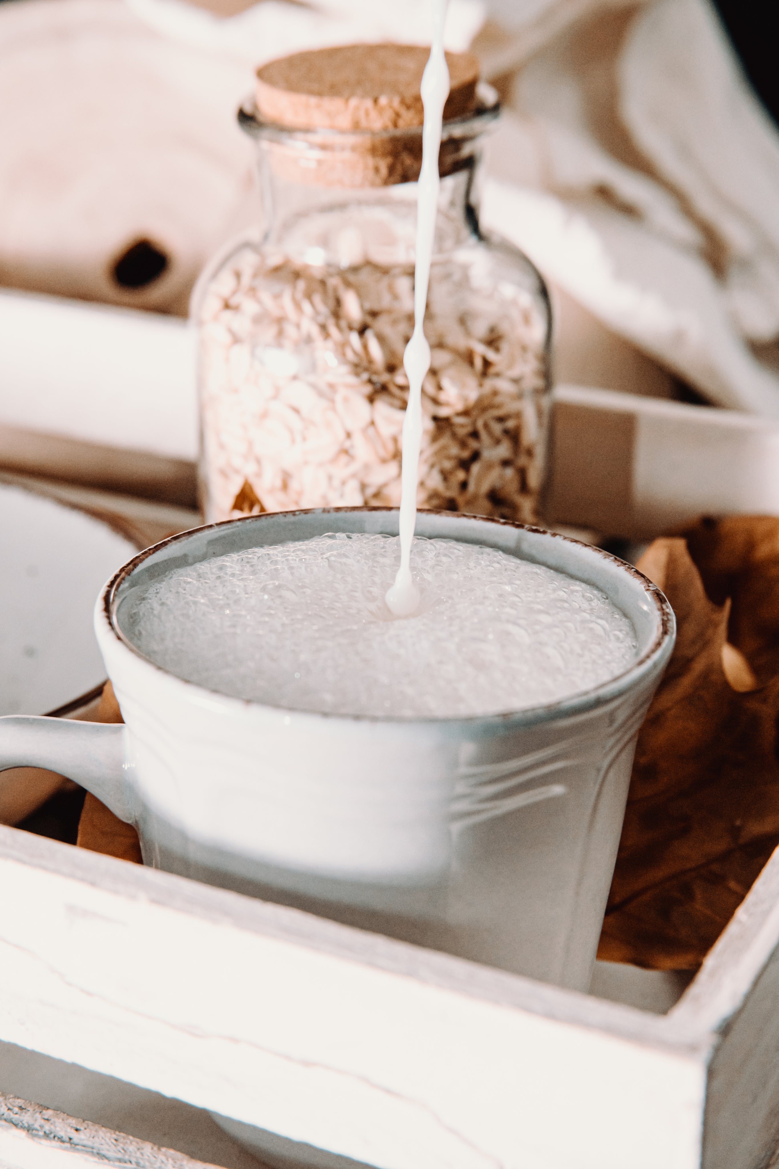 frothy-milk-pouring-into-a-ceramic-mug-on-wooden-tray - REGEN